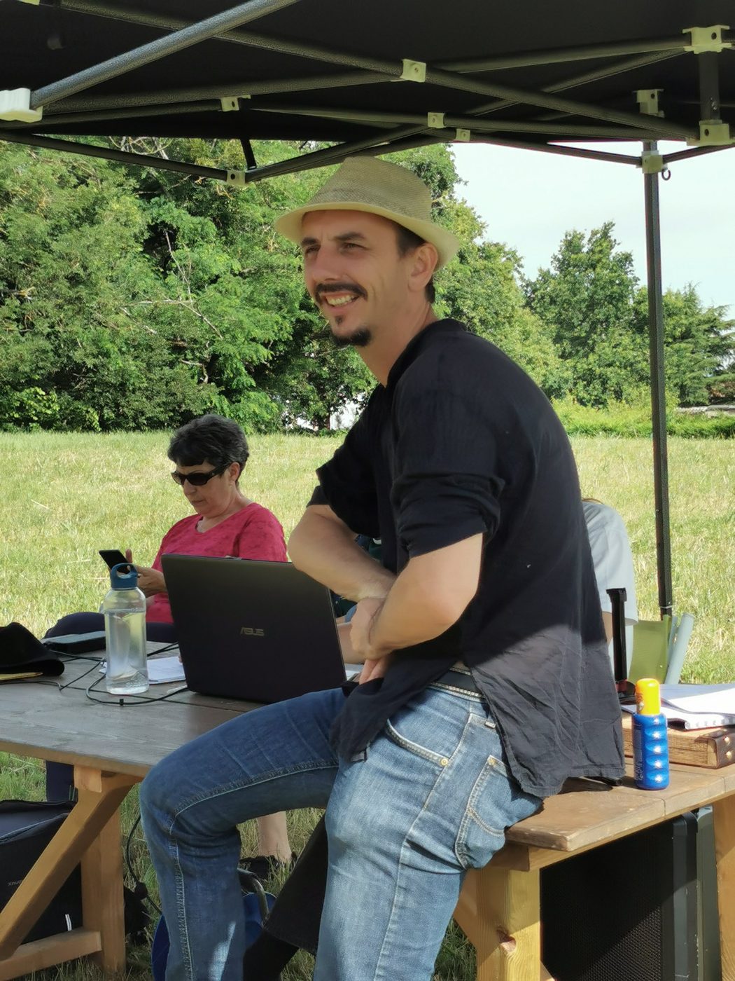 Gaël Dubreuil souriant, assis sur une table de régie sous un barnum