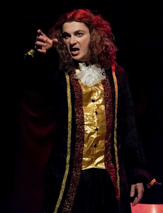 Molière, perruque rousse, pointe un doigt accusateur