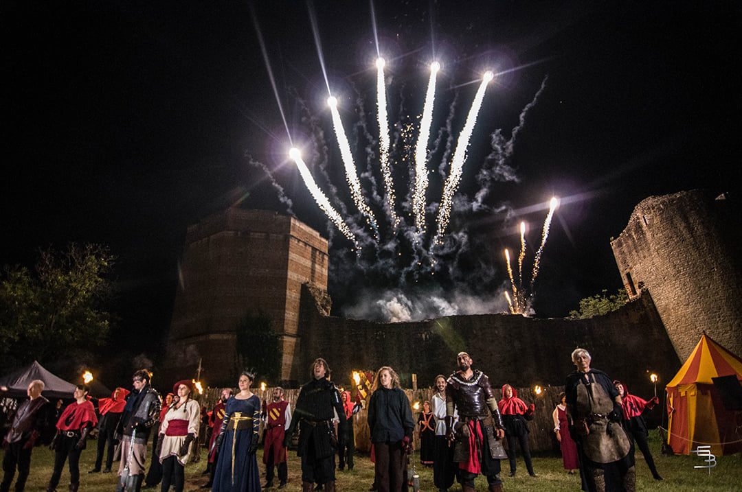 Final d'un spectacle au château : comédiens en costumes médiévaux alignés sous un feu d'artifice